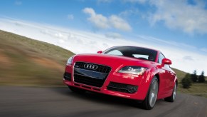 A low-angle shot of a red 2008 Audi TT Coupe driving down a road