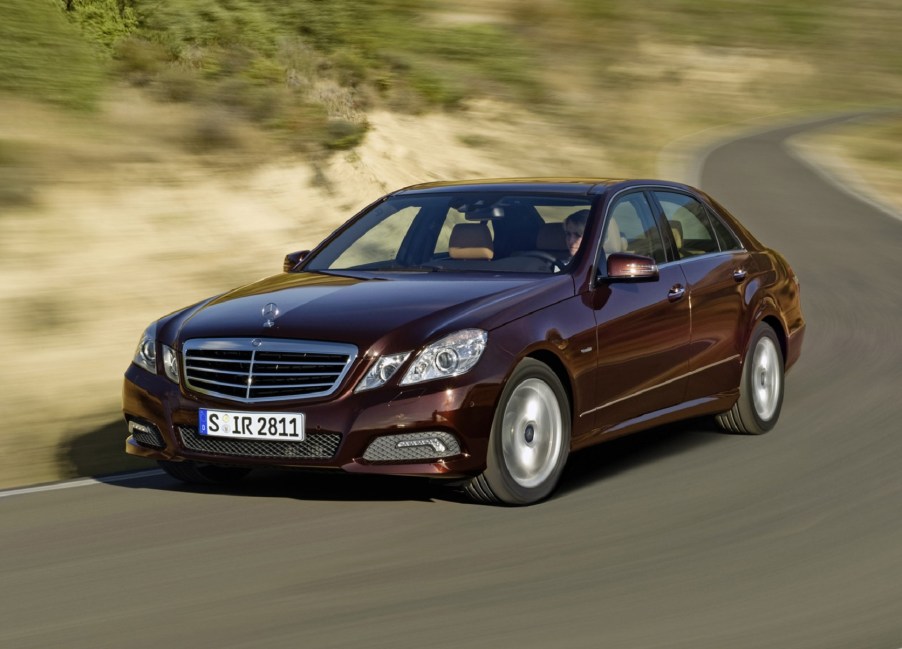 Burgundy-red 2010 Mercedes-Benz E-Class sedan driving down a curving road