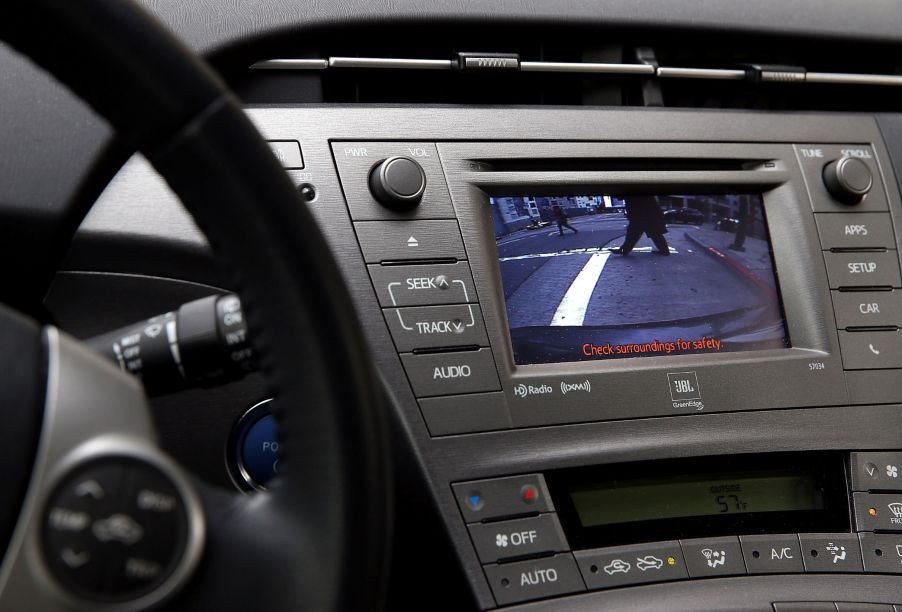 The backup camera display of a 2014 Toyota Prius, showing passing pedestrians