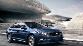 A blue, used 2016 Hyundai Sonata cruises a city street.