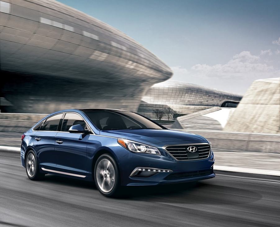 A blue, used 2016 Hyundai Sonata cruises a city street.