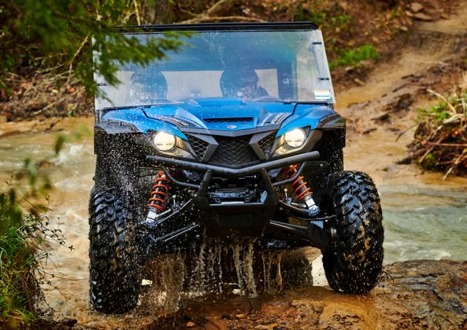 a Yamaha Wolverine UTV splashing through a creek bed