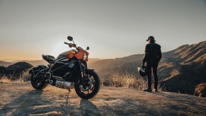 Orange 2020 Harley-Davidson LiveWire with its rider in the background, both watching the rising sun over a canyon