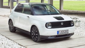 A white 2021 Honda E next to a concrete structure and grass