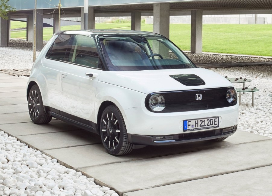 A white 2021 Honda E next to a concrete structure and grass