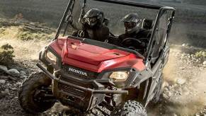 a red Honda UTV Pioneer 1000 LE climbing rocky terrain