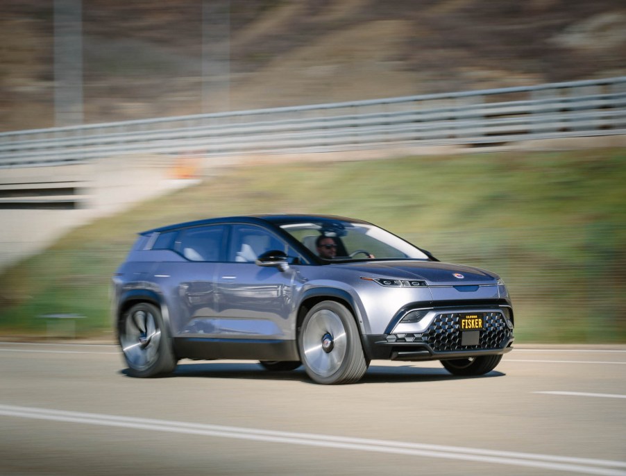 A silver Fisker electric SUV makes a hillside pass.