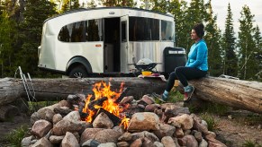 The Airstream Basecamp travel trailer is parked by a campfire.