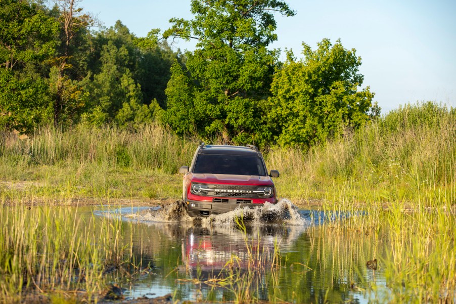 The Ford Bronco Sport, like this red one fording a deep puddle, is wild enough for most climbers