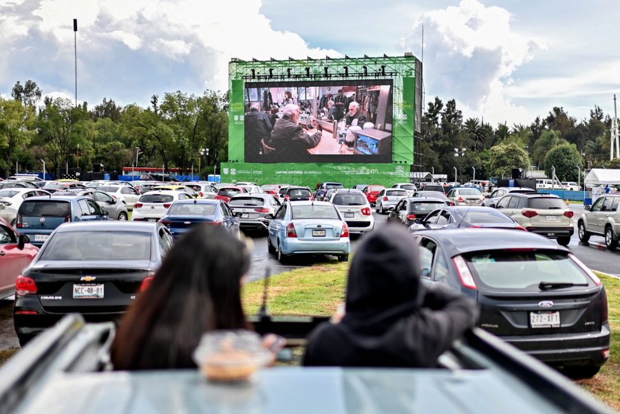 Two people stick their head out the sunroof to watch a drive-in movie