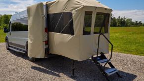 The rear of an RV has a porch tent platform.