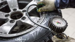 A mechanic measures a tire's pressure using a handheld gauge