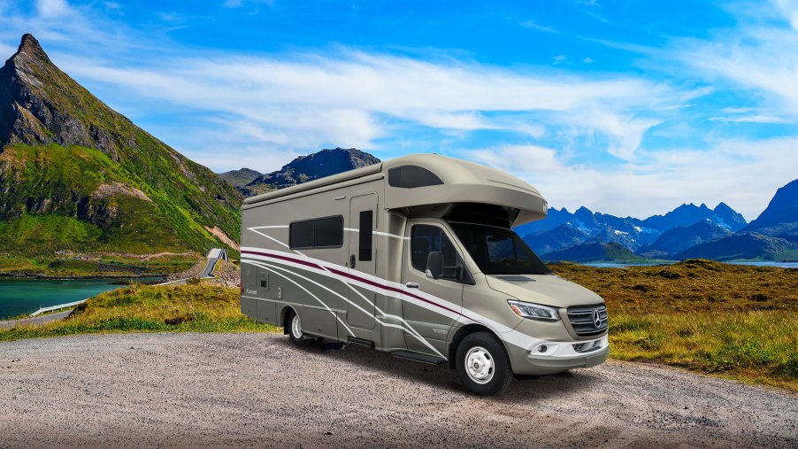 A Winnebago Navion RV sits in a valley on a nice blue-sky day.