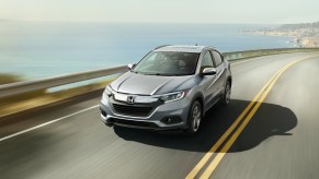 a silver top trim HR-V driving fast on a scene road by the shore