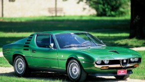 A green 1970 Alfa Romeo Montreal on a manicured estate lawn