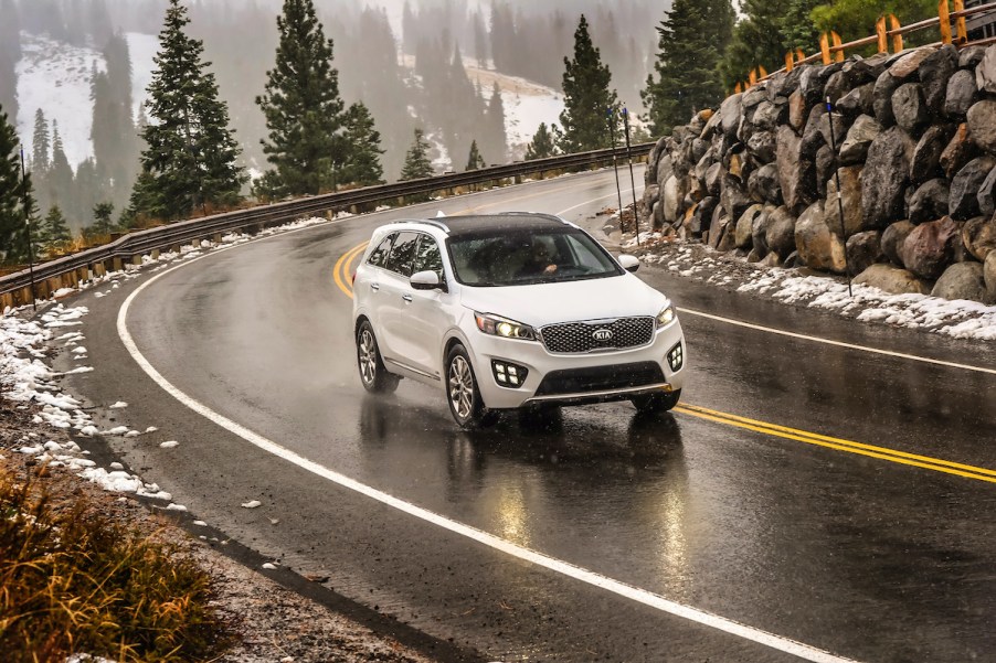 2017 Kia Sorento driving through a snowy and icy mountain road with evergreen trees and rocks in the background