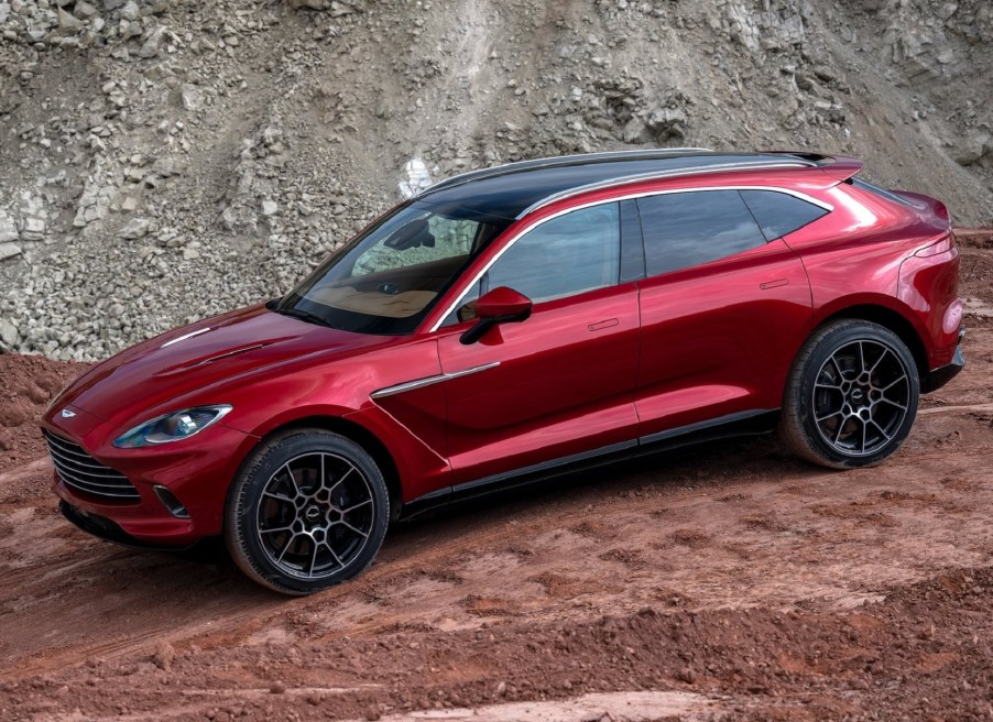 The side view of a red 2021 Aston Martin DBX as it descends a rocky trail