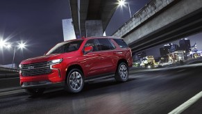 A red 2021 Chevrolet Tahoe drives on a city's highway at night