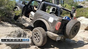 A black 2-door 2021 Ford Bronco with its doors and roof removed scrambles up a rocky incline on the Rubicon Trail