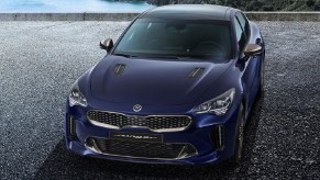 A dark-blue 2022 Kia Stinger on a rocky ocean overlook