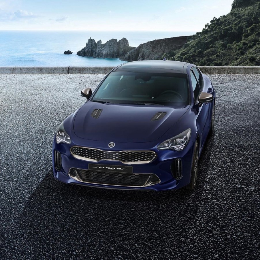 A dark-blue 2022 Kia Stinger on a rocky ocean overlook