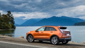 Cadillac XT4 Sport driving alongside a lake and a mountain in the back