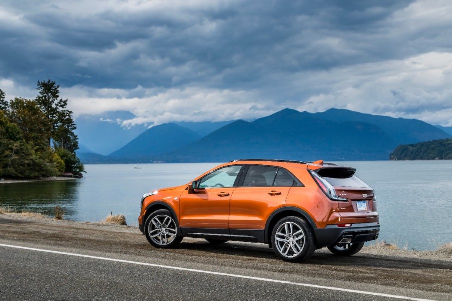 Cadillac XT4 Sport driving alongside a lake and a mountain in the back