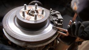 A mechanic checks a Range Rover Evoque's brake disc thickness, with the brake pad still attached