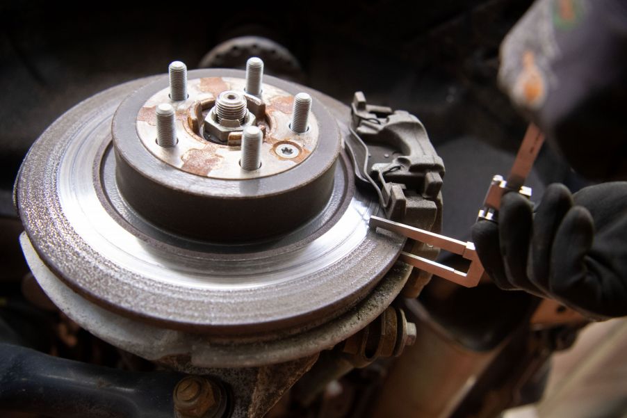 A mechanic checks a Range Rover Evoque's brake disc thickness, with the brake pad still attached