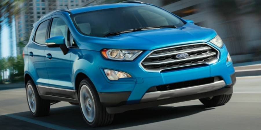 A blue 2018 Ford EcoSport subcompact SUV is driving on the road.