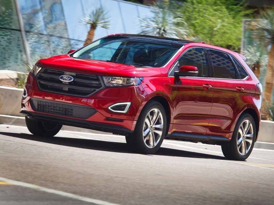 A red 2015 Ford Edge parked by a glass building.