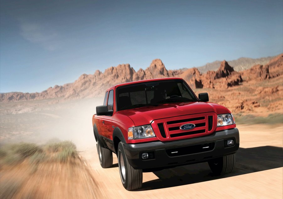 a red Ford Ranger pickup travels down a dirt road.