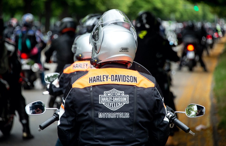 Motorcyclists wearing Harley-Davidson jackets stand on the banks of the Rudolf-von-Bennigsen river during a demonstration ride