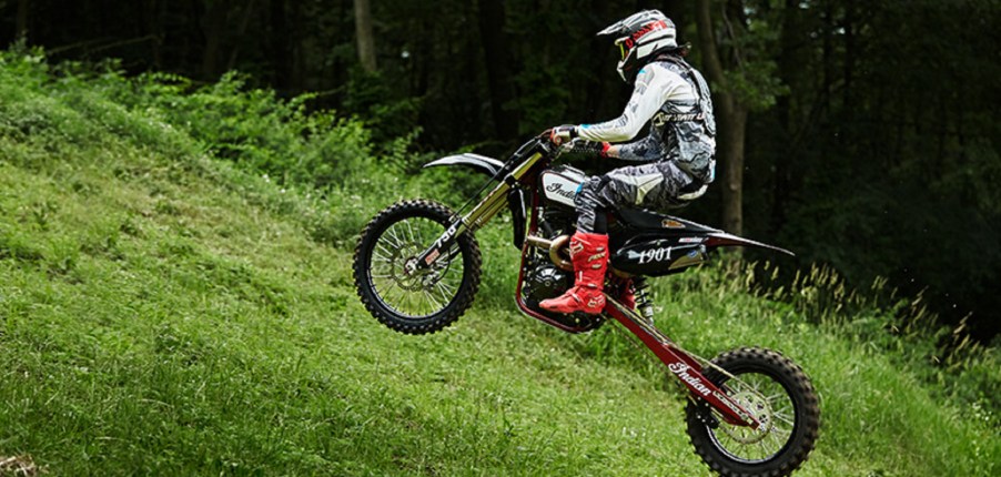 A black Indian FTR750 hill climb bike speeds up a grassy hill