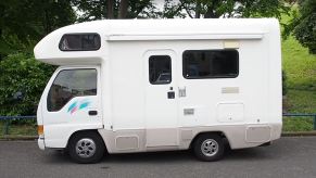 A small, white Isuzu RV is viewed from the driver's side.