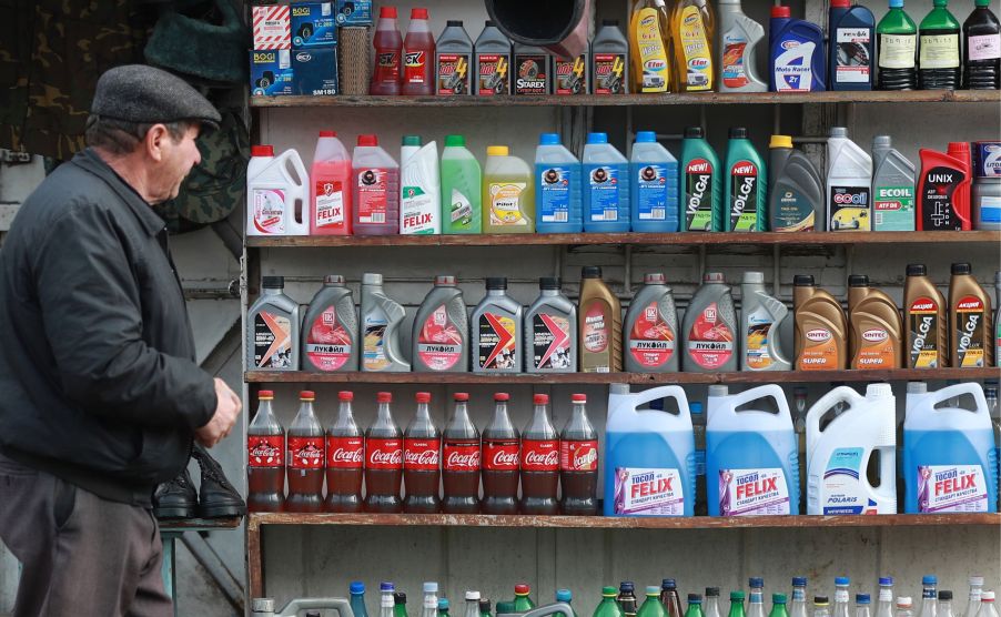 Bottles of different coolant colors on shelves, along with oil and other automotive fluids