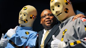 An NHTSA employee poses with the crash test dummies.