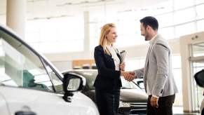 Salesperson showing vehicle to potential customer in dealership; Shutterstock ID 447213895; Purchase Order: -