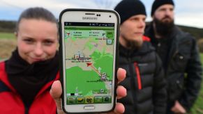 Amateur 'treasure hunters' Franziska Dennstedt (L-R), presenting her GPS capable smartphone and co-treasure hunters Sebastian Schwarz and Peter Scharf take part in an electronic treasure hunt near Klettbach, Germany, 29 January 2016. Geocaching is becoming increasingly popular in the state of Thuringia. According to the Thuringia's geocaching association, there are around 4,000 geocaching enthusiasts who regularly go on tour using their GPS to detect caches. Photo: Martin Schutt/dpa | usage worldwide (Photo by Martin Schutt/picture alliance via Getty Image