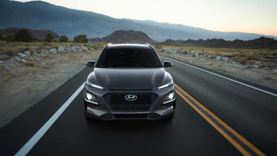 a gray Hyundai Kona driving on a deserted two-lane straightaway highway exemplifies that Hyundai readily competes with a Honda or Toyota