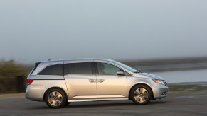 a silver Honda Odyssey driving near the shore. It's a great choice for a used minivan