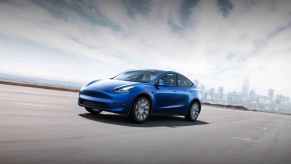 An image of a blue Tesla Model Y driving down the road.