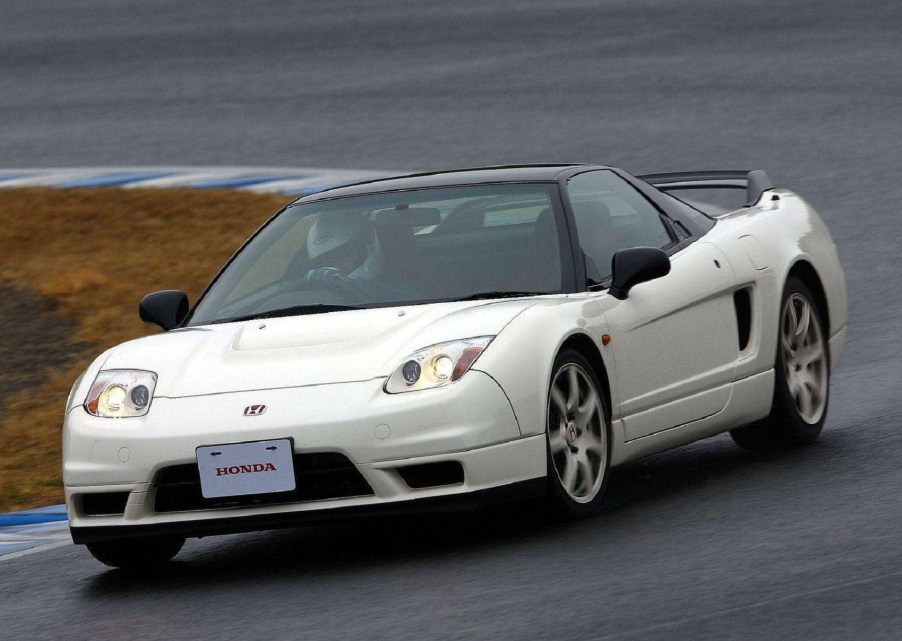 A white 2002 Honda NSX Type R goes around a rainy racetrack corner