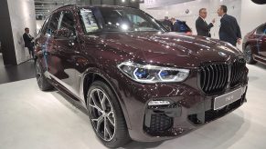 A maroon BMW X5 on display at an auto show