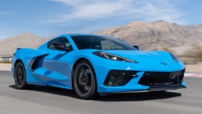 A blue 2020 Chevrolet Corvette C8 Stingray races around a desert racetrack