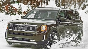 A green 2020 Kia Telluride drives through the snow