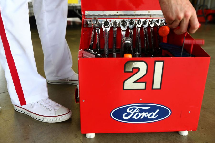 A white-suited NASCAR mechanic reached into their red open toolbox