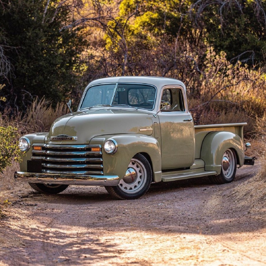 A green-and-vanilla Icon 4x4 Old School Edition Thriftmaster pickup in a sunlit forest