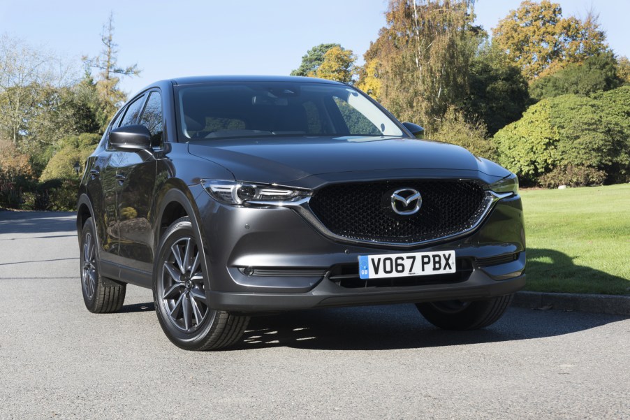 A black Mazda CX-5 parked and on display with trees in the background.