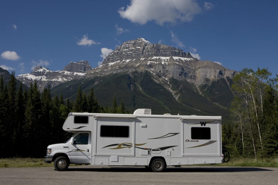 A motorhome RV camper parked on a road in front of a mountain